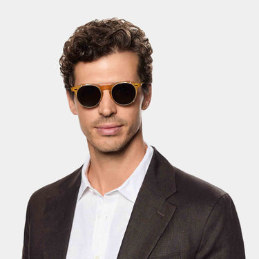 A man wearing Pleat sunglasses by TBD Eyewear Honey Gold bio-acetate frame with Bottle Green lenses, handcrafted in Italy