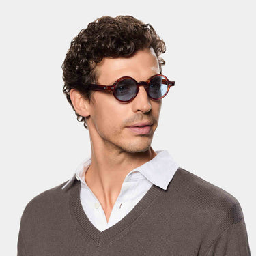 A man wearing sustainable Oxford sunglasses by TBD Eyewear in Eco Havana with Blue lenses – crafted from bio-acetate and handcrafted in Italy.