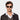 A man wearing sustainable Cran sunglasses by TBD Eyewear in Eco Transparent and Bottle Green lenses crafted from bio-acetate and made in Italy