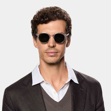A man wearing sustainable Cran sunglasses by TBD Eyewear in Eco Transparent and Bottle Green lenses crafted from bio-acetate and made in Italy