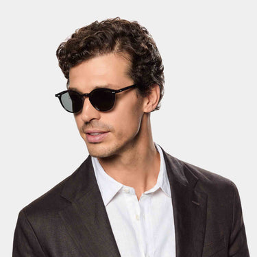 A man wearing sustainable Cran sunglasses by TBD Eyewear in Eco Black Gradient Grey made from bio-acetate and made in Italy