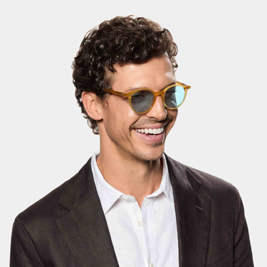 A smiling man wearing Cran sunglasses by TBD Eyewear in Honey frame and blue lenses in bio-acetate materials and made in Italy