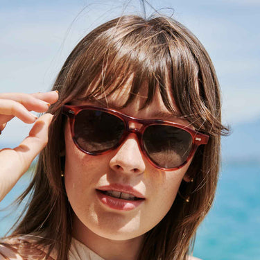 A woman with Piquet Havana sunglasses in bio-acetate, featuring bottle green lenses by Tbd Eyewear